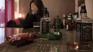 Eine Frau sitzt an einem Tische mit mehreren Falschen Whiskey (Foto: imago images/Hans Luicas)