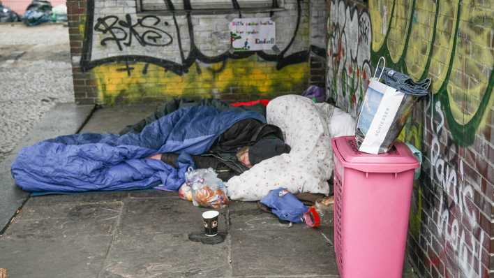 Ein obdachloser Mann schläft auf der Straße an einer Häuserwand (Foto: imago images/Rolf Kremming)
