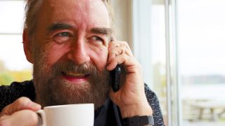 ei Mann sitzt mit einer Kaffeetasse und einem Telefonhörer in der Hand an einem Fenster (Foto:Privat)