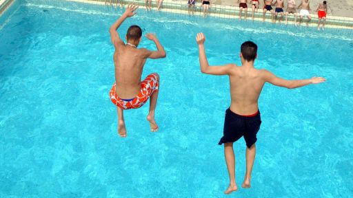 Zwei Jugendliche springen in ein Schwimmbecken (Foto: imago/Sven Lambert)