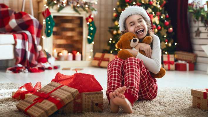 Ein Kind mit Weihnachtsmütze freut sich über einen Teddybären (Foto: colourbox) Ein Kind mit Weihnachtsmütze freut sich über einen Teddybären (Foto: colourbox)