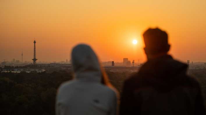 Zwei Menschen schauen sich auf dem Drachenberg den Sonnenaufgang über Berlin an. (Quelle: dpa/Christophe Gateau) Zwei Menschen schauen sich auf dem Drachenberg den Sonnenaufgang über Berlin an. (Quelle: dpa/Christophe Gateau)