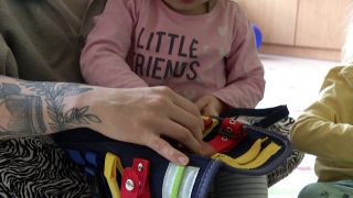 Eine Betreuerin der Kinderhilfe KileLe hat ein kleines Kind auf dem Schoß. (Quelle: rbb)