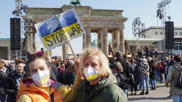 Teilnehmer der Solidaritätskundgebung "Sound of Peace" vor dem Brandenburger Tor halten ein Plakat mit der Aufschrift "Stop War" und den ukrainischen Landesfarben. (Quelle: dpa/Jörg Carstensen)